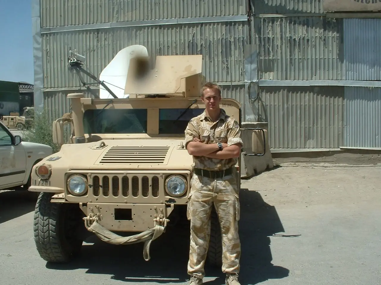 Michael standing beside a military vehicle during his Royal Marines service